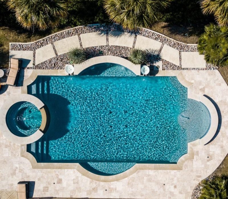 Aerial view of custom curved swimming pool with integrated spa and tropical landscaping by Leisure Living Pools luxury pool builders Dallas